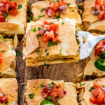 sheet pan quesadilla cut into pieces on a cutting board topped with pico de gallo.