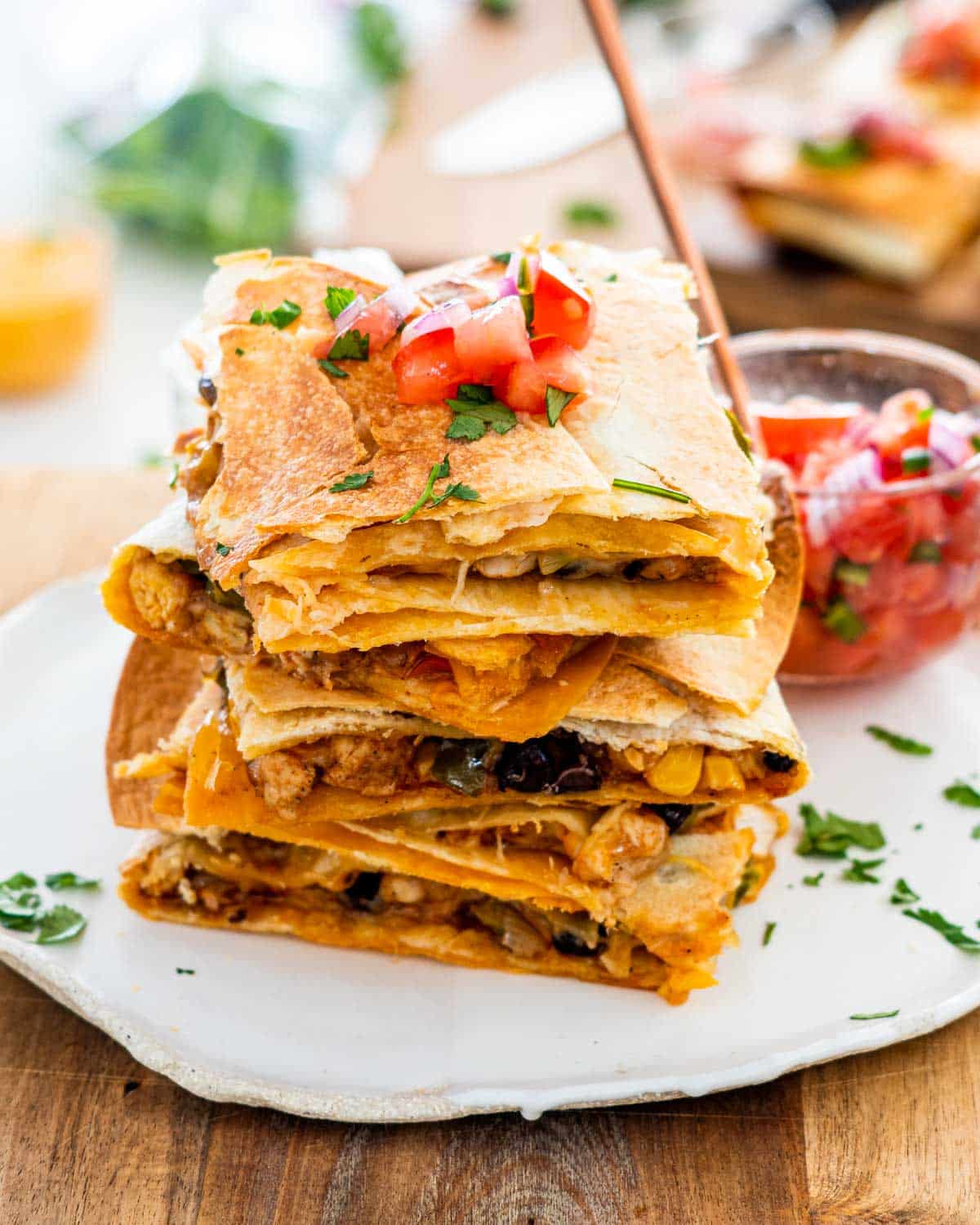 four quesadilla stacked on top of each other topped with pico de gallo.
