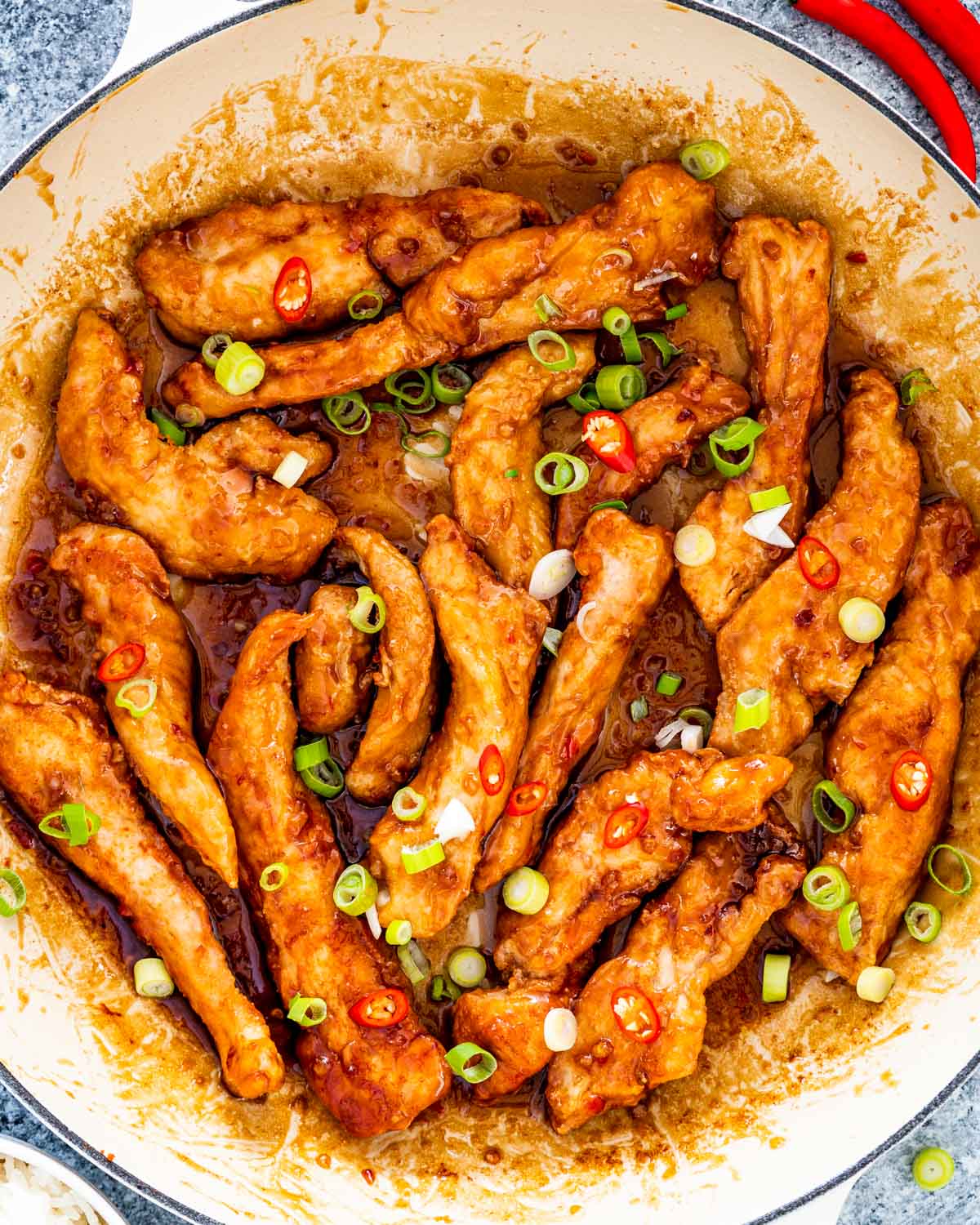 sweet chili chicken in a skillet garnished with green onions.