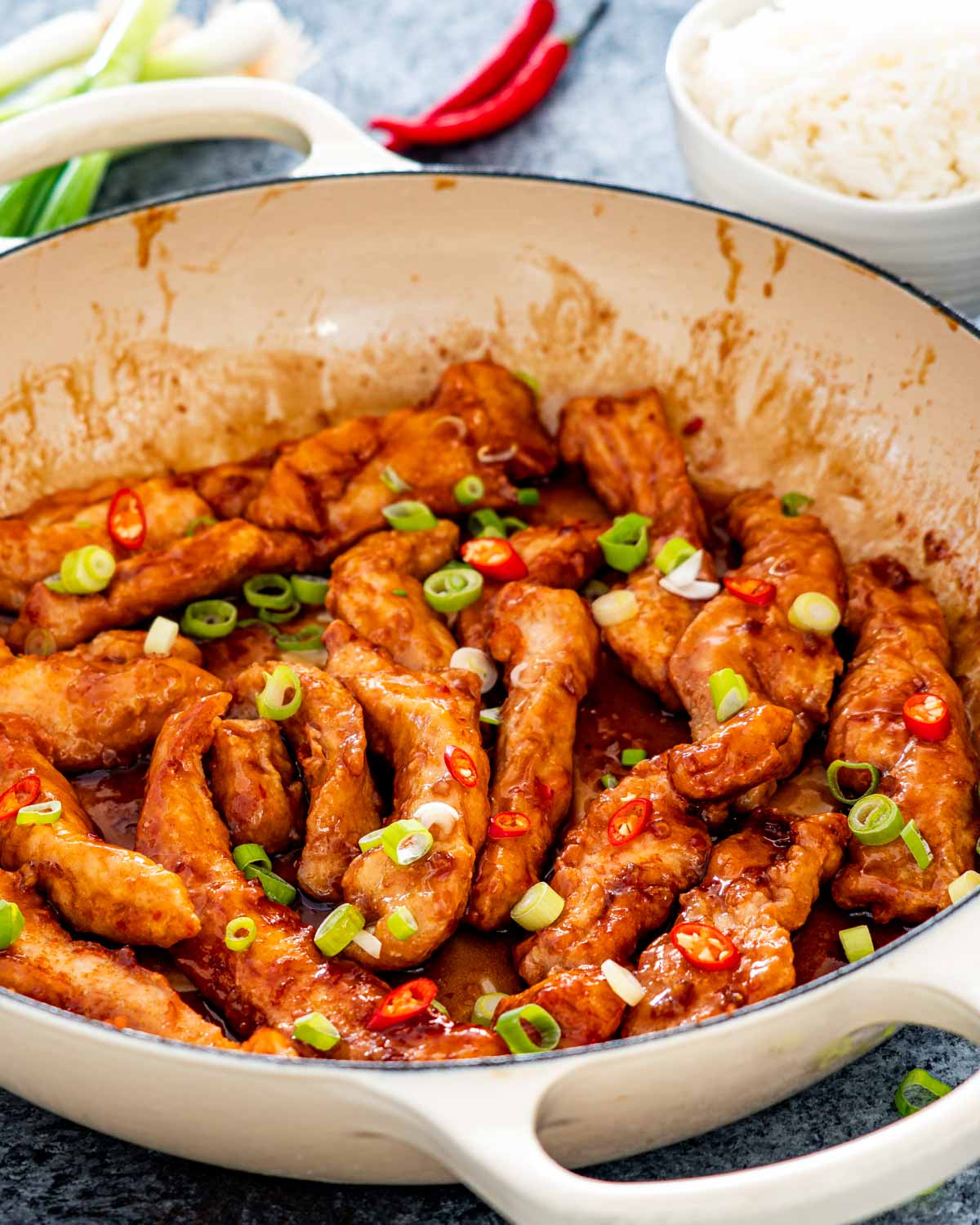 sweet chili chicken in a skillet garnished with green onions.
