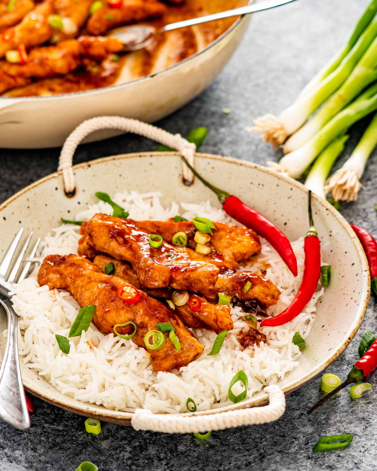 sweet chili chicken on a bed of rice garnished with green onions.