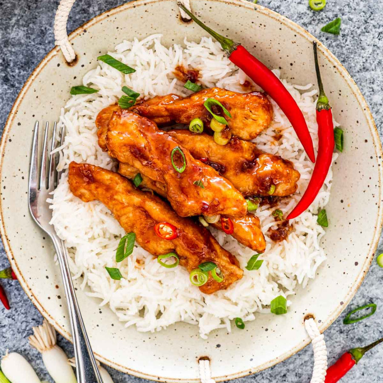sweet chili chicken on a bed of rice garnished with green onions.