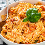 baked feta pasta in a white bowl garnished with fresh basil.