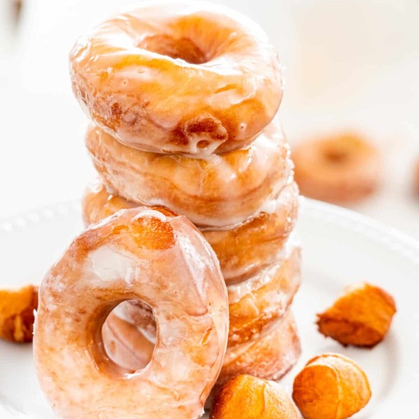 a stack of glazed donuts on a white plate.