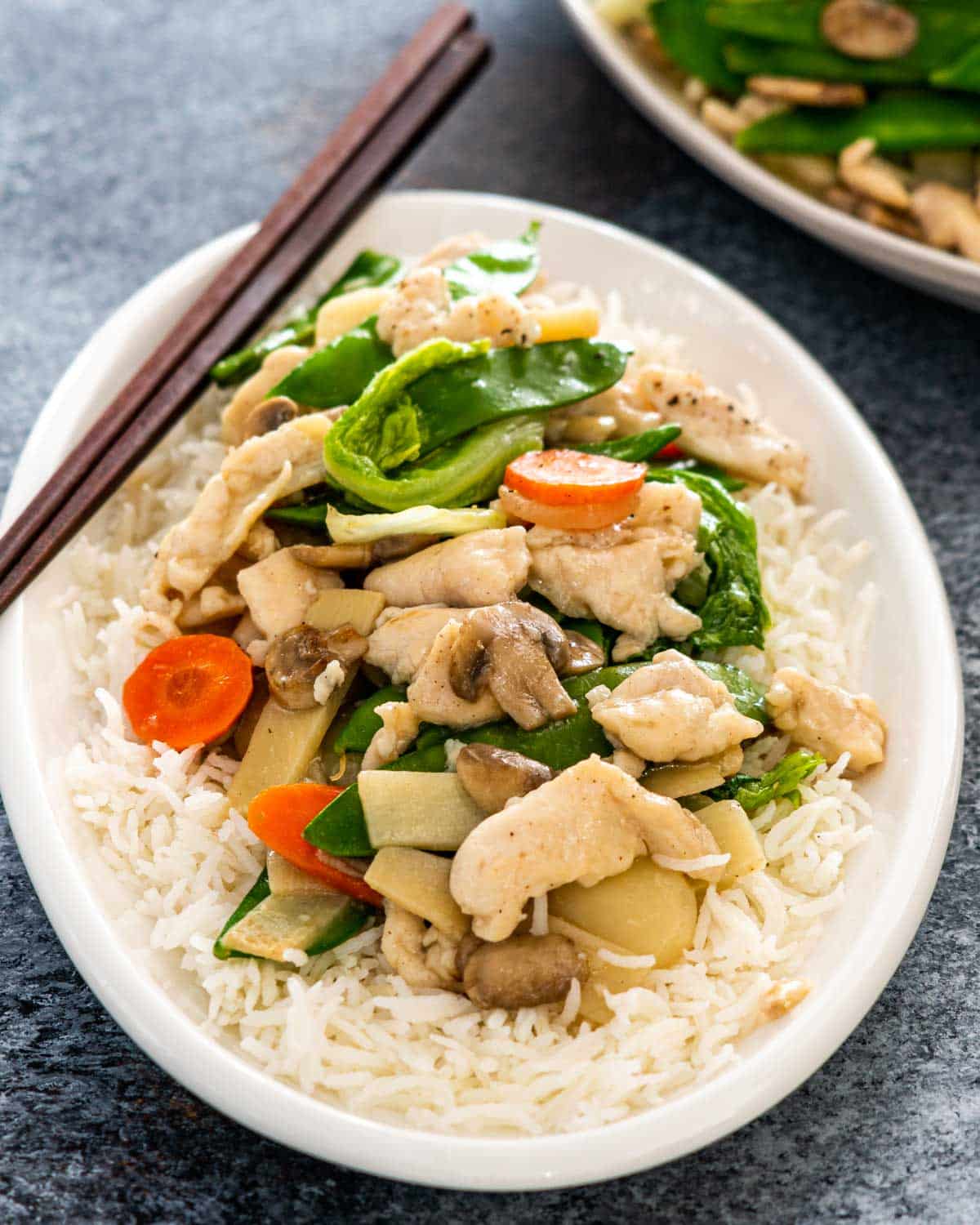 moo goo gai pan over rice on a white plate.