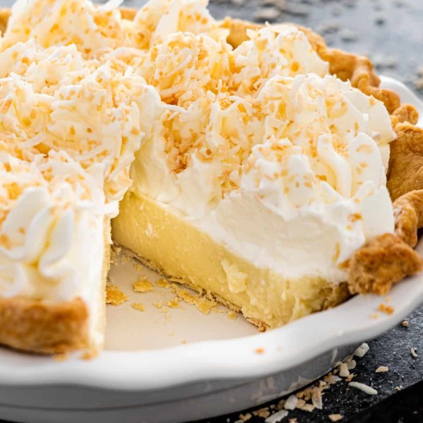 a coconut cream pie in a pie plate with a piece missing.