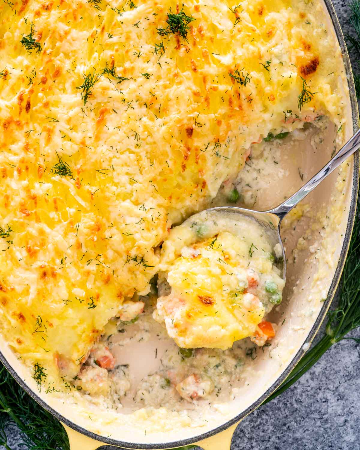 freshly baked fish pie in a casserole dish with a serving spoon inside.