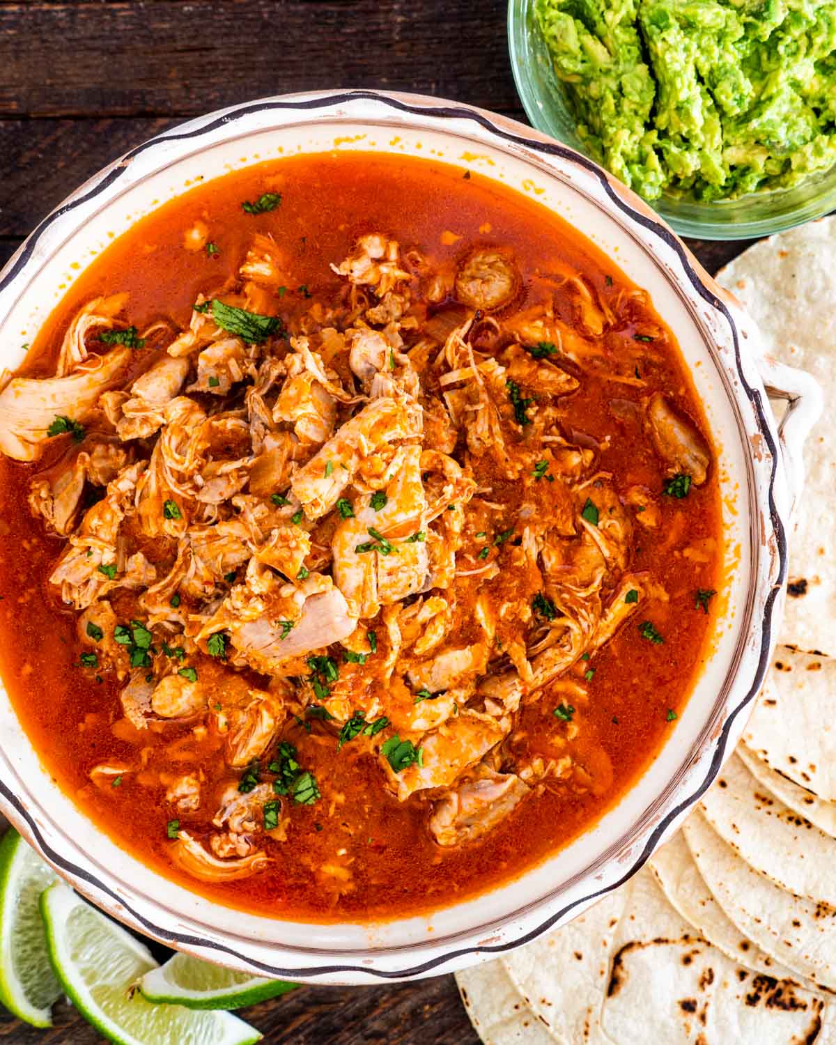 chicken tinga in a bowl with some tortillas around the bowl.