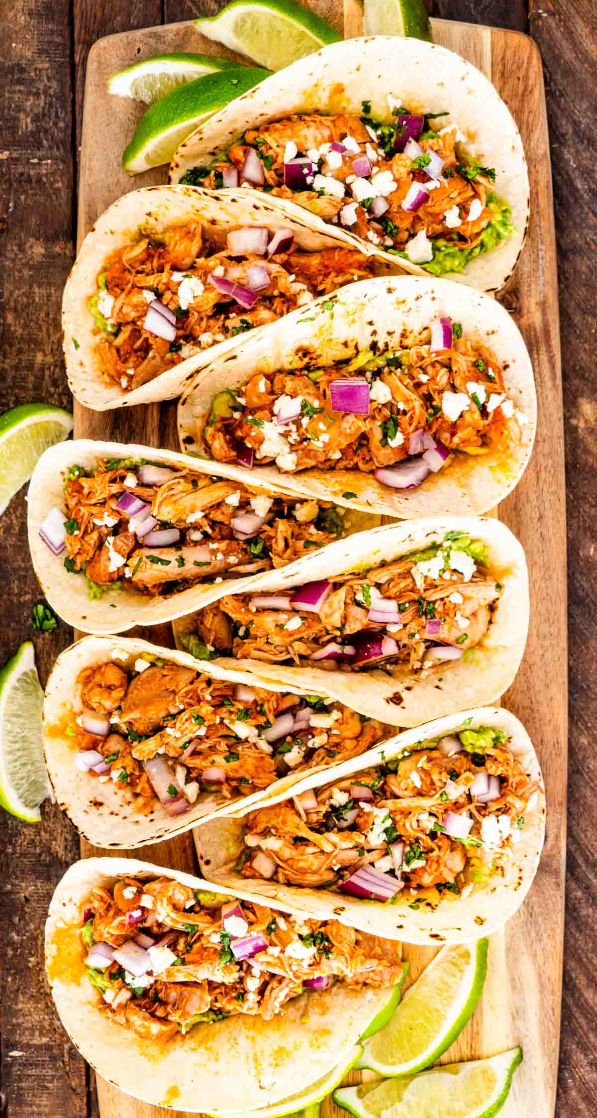 a row of chicken tinga tacos on a cutting board.