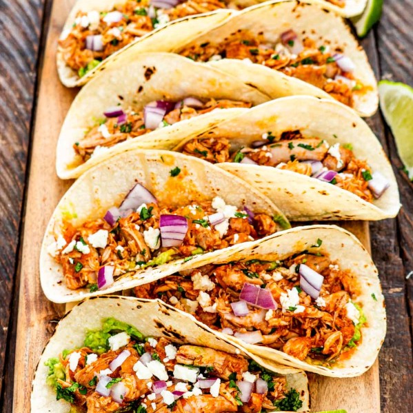 a row of chicken tinga tacos on a cutting board.
