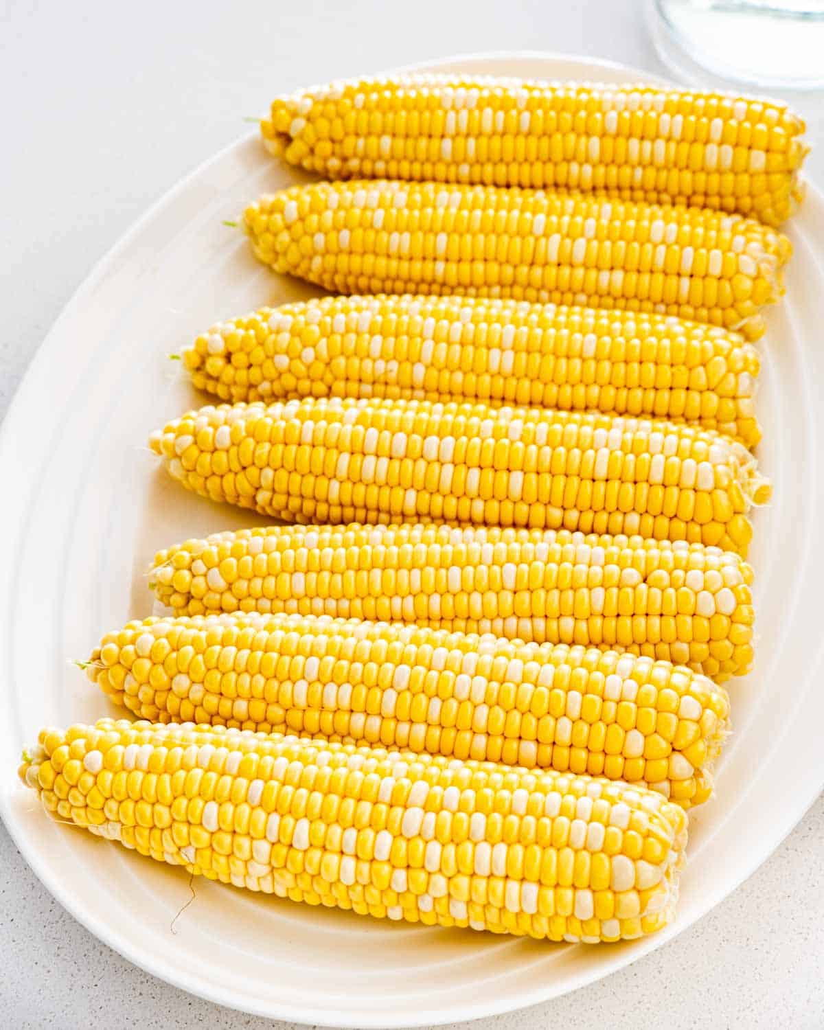 7 ears of corn on a white serve plate.