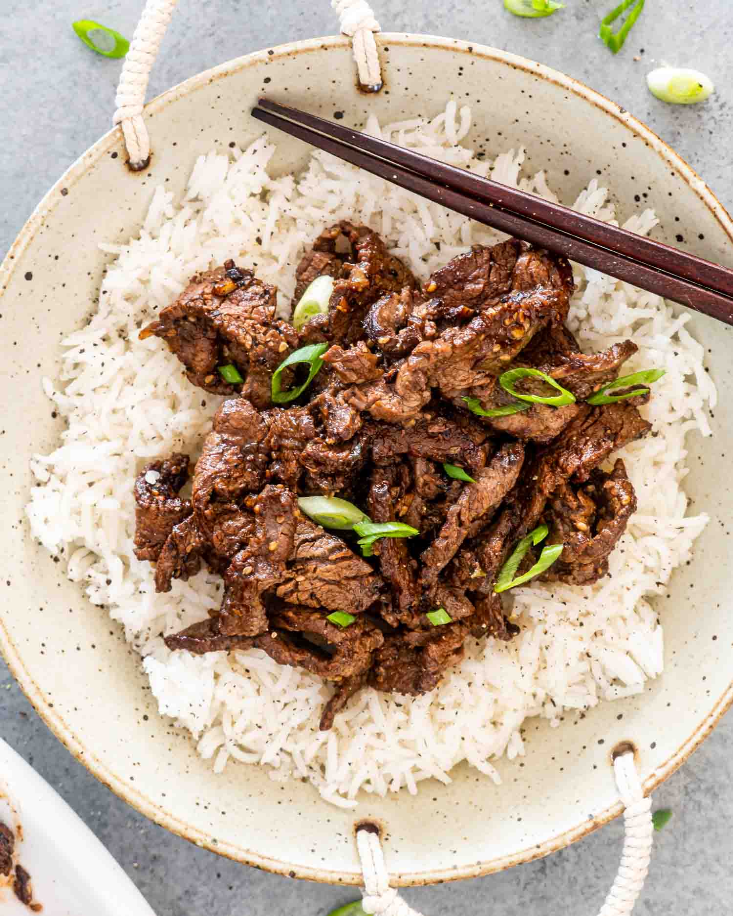 beef bulgogi over a bed of rice garnished with green onions.