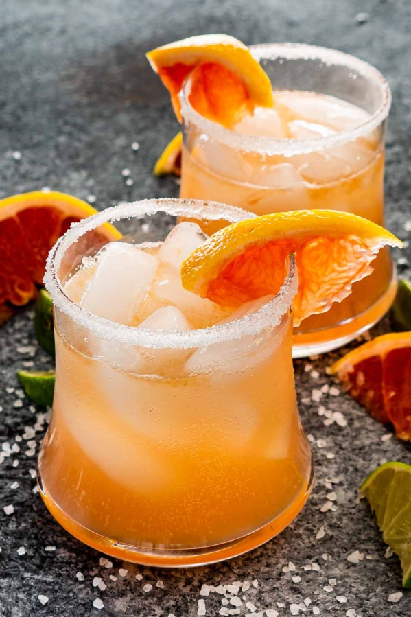 two glasses filled with paloma and garnished with grapefruit slice.