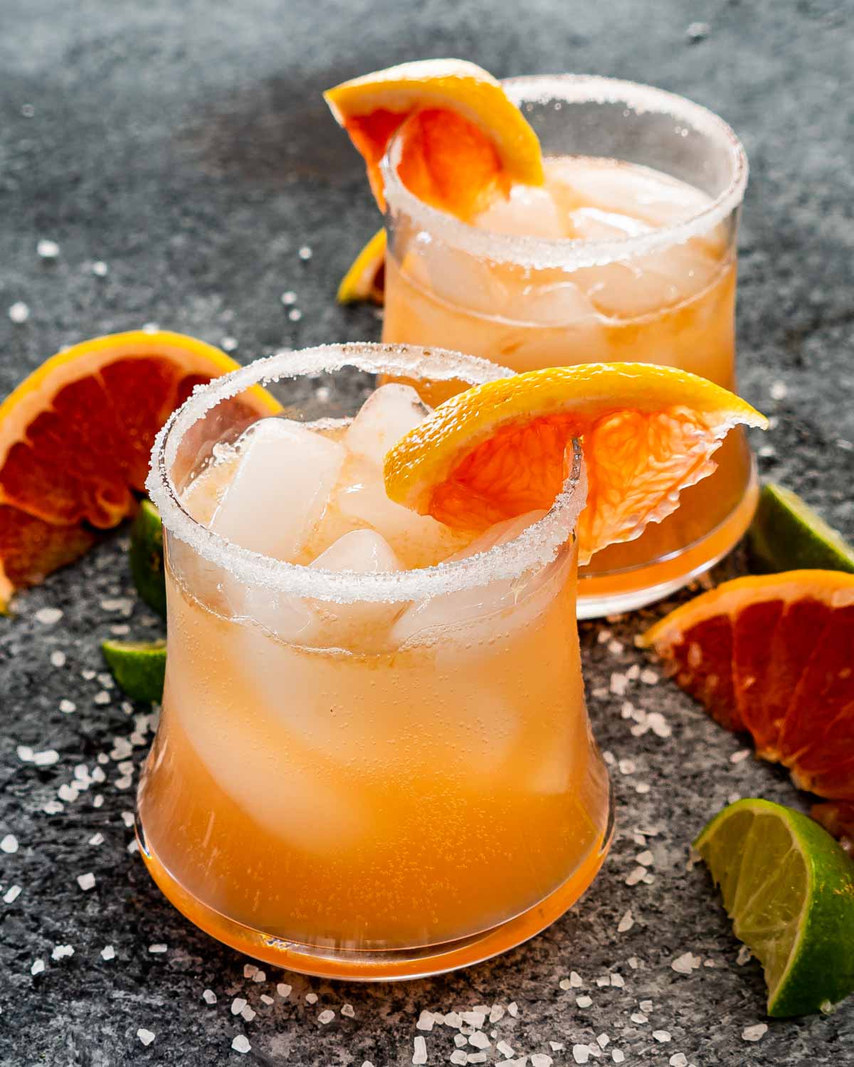 two glasses filled with paloma and garnished with grapefruit slice.