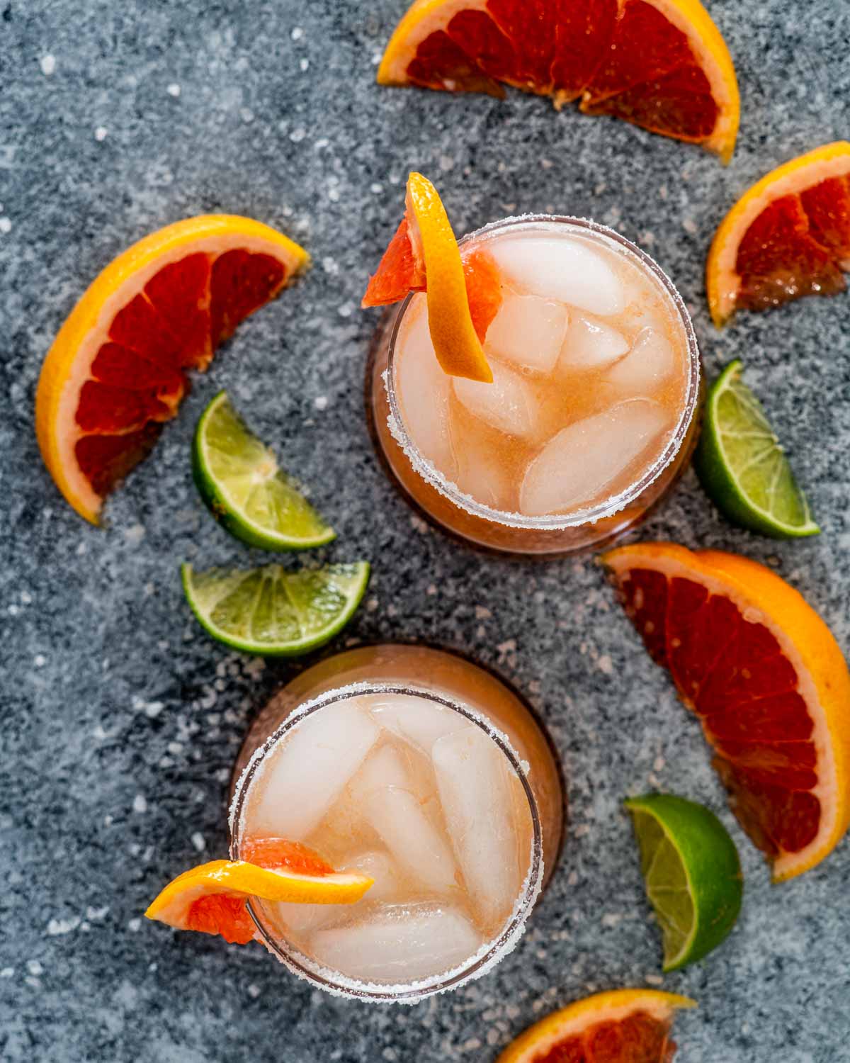 overhead shot of two paloma cocktails surrounded by grapefruit wedges.