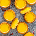 a bunch of egg tarts on a table with one cut in half.