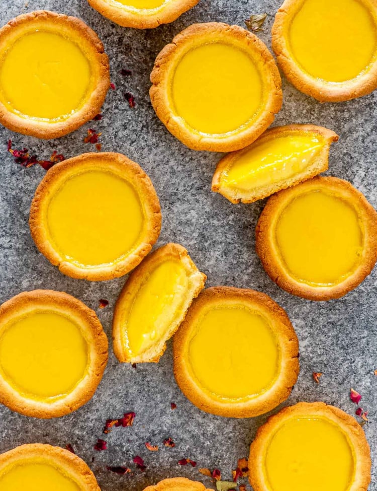 a bunch of egg tarts on a table with one cut in half.