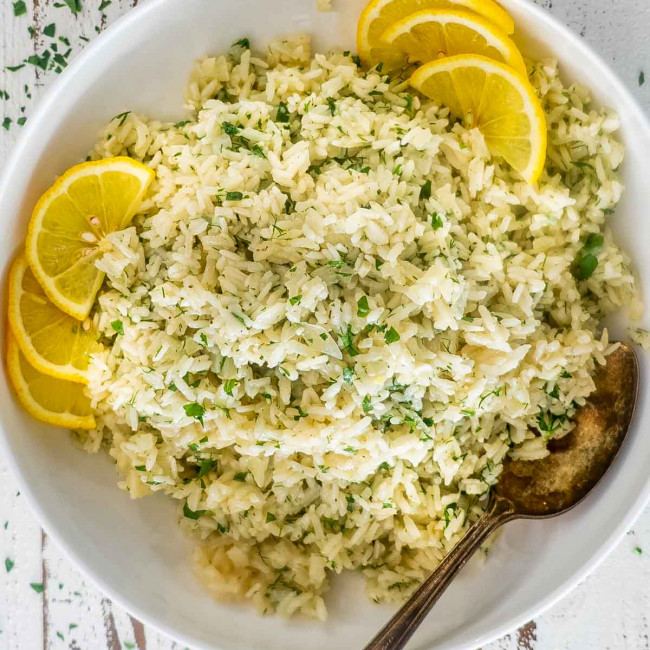 greek rice in a white bowl garnished with lemon slices.