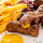 mititei on a plate with mustard and french fries.
