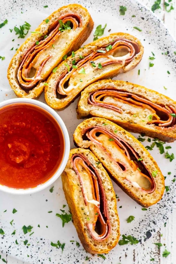 a few pices of stromboli on a plate with a bowl with marinara.