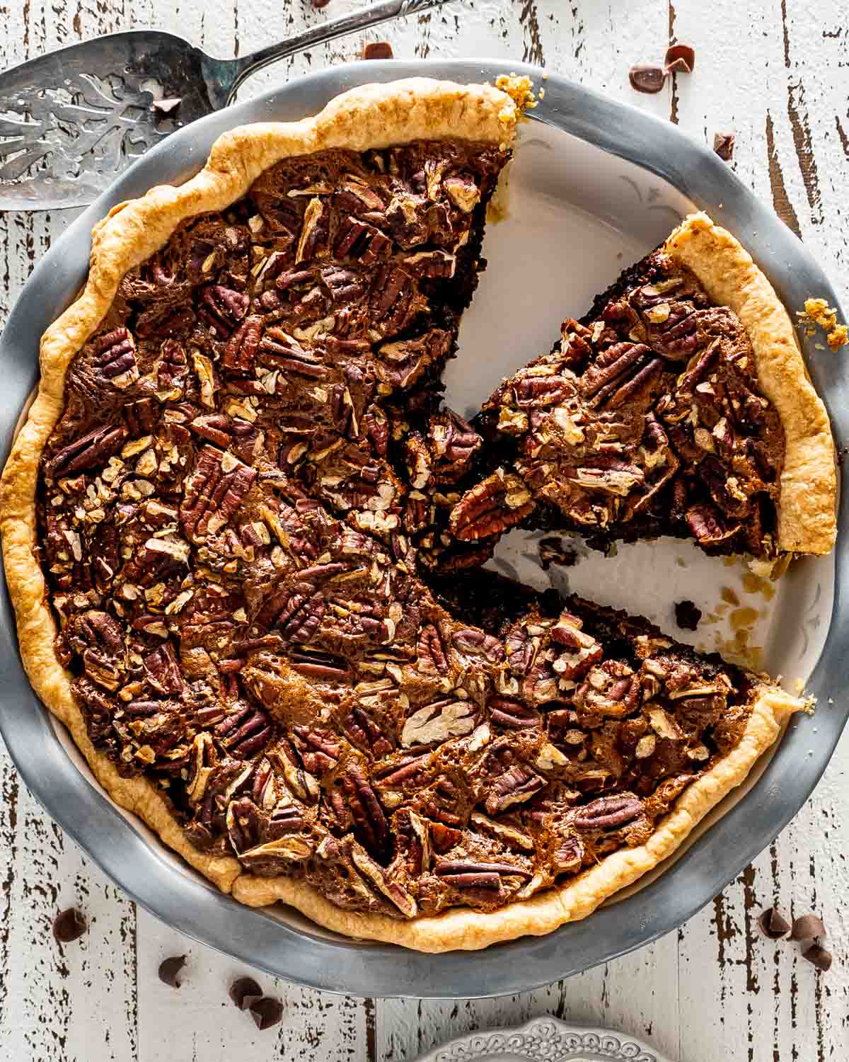 freshly baked chocolate pecan pie in a pie plate with a slice cut out.
