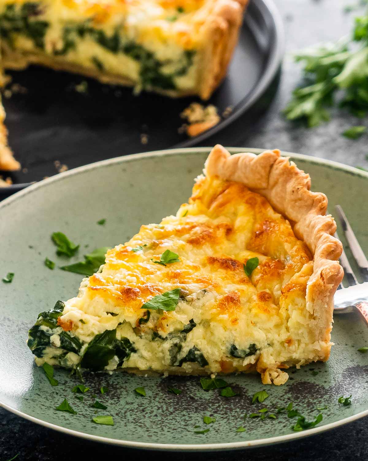 a slice of quiche florentine on a green plate.