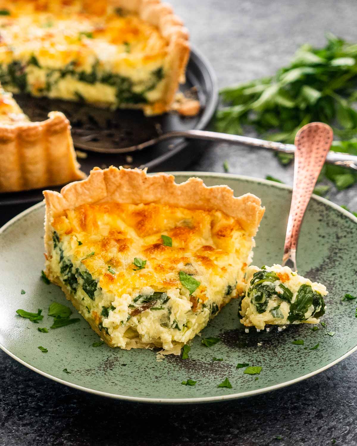 a slice of quiche florentine on a green plate.