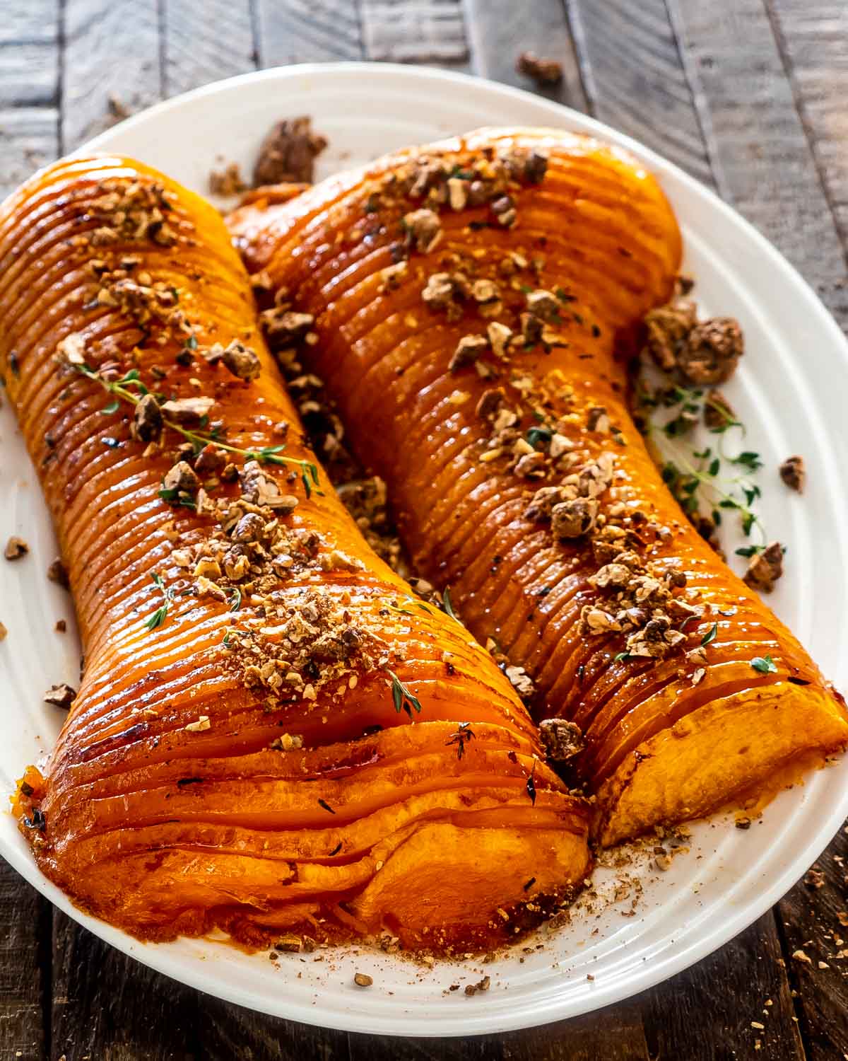two halves of a honey roasted butternut squash on a platter roasted with sugar pecans.
