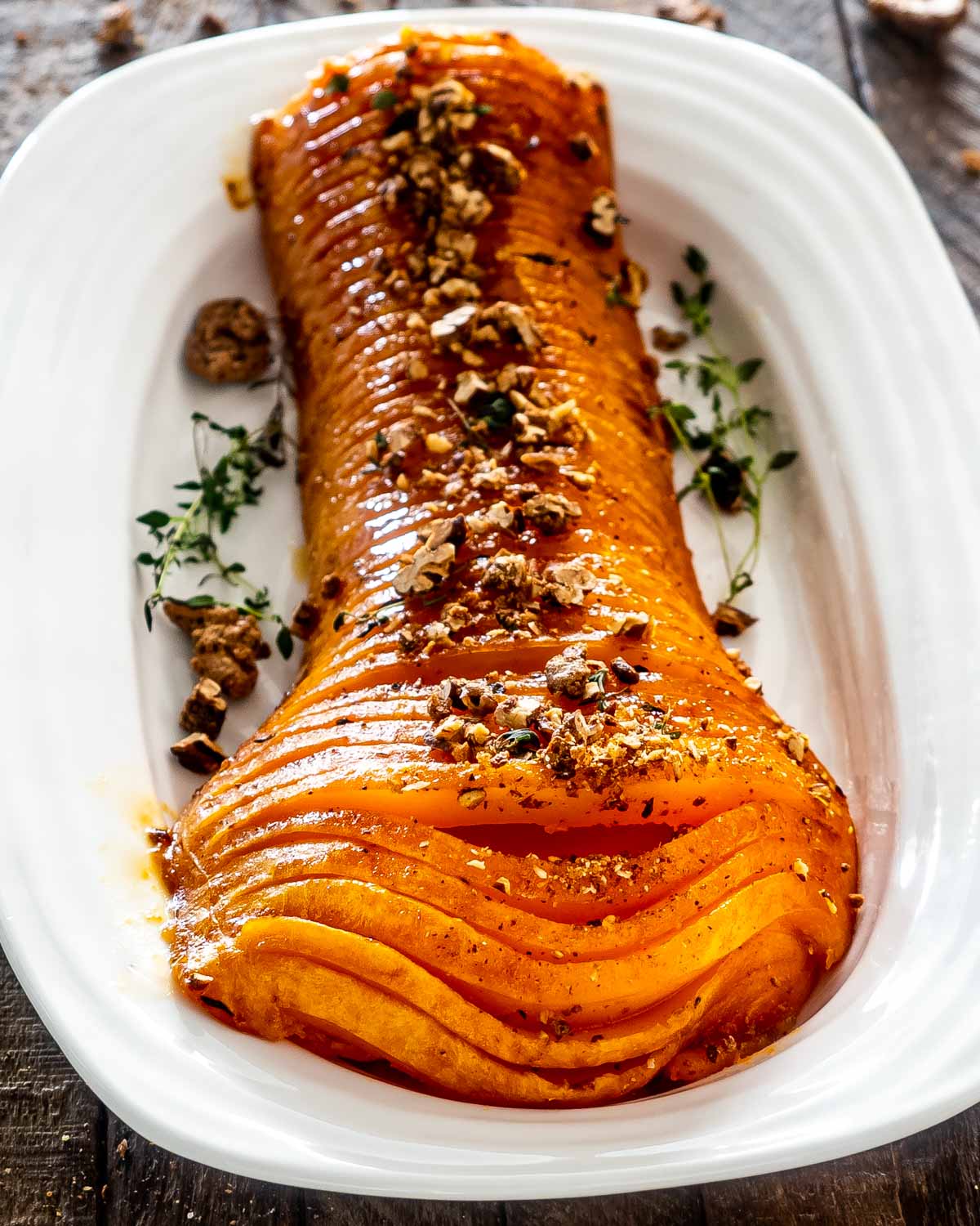 one half of a honey roasted butternut squash on a platter roasted with sugar pecans.