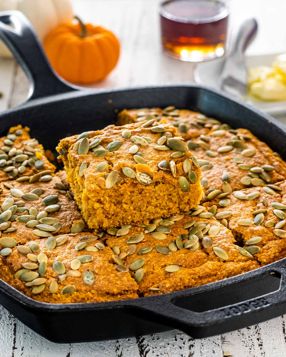 a skillet with pumpkin maple cornbread topped with pepitas and cut into slices.