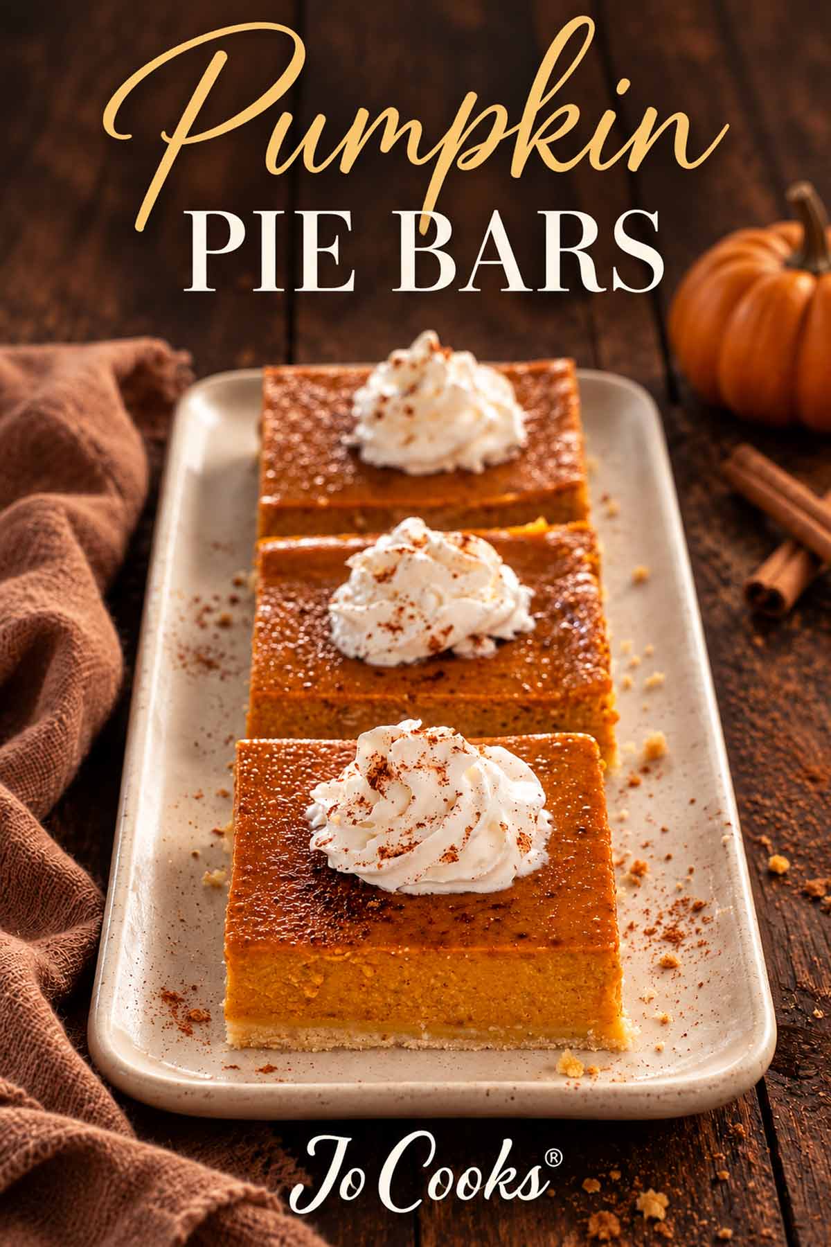 Three pumpkin pie bars with whipped cream on a platter, beneath Pumpkin Pie Bars text, with Jo Cooks logo below.