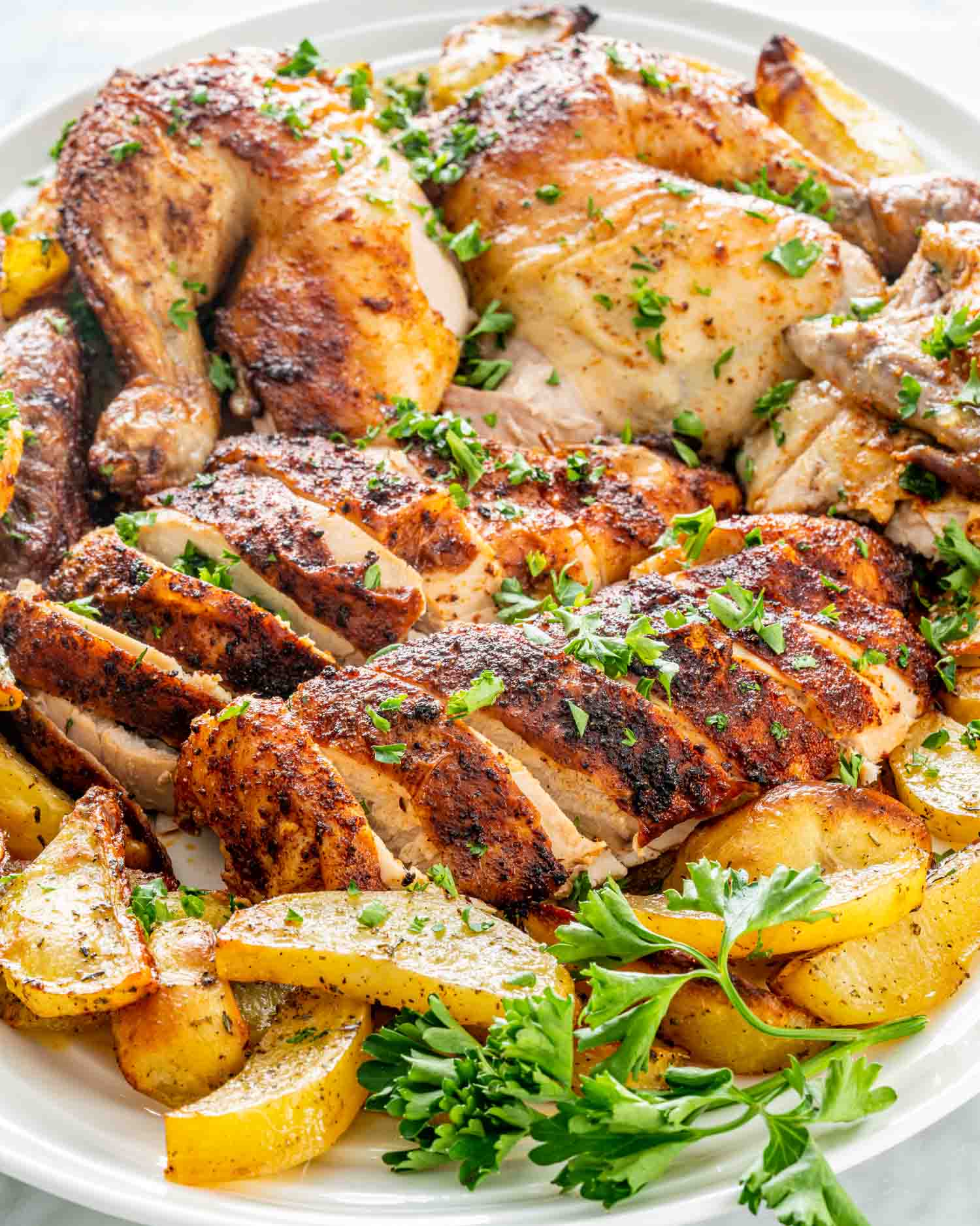 a roast chicken carved up on a platter with some roasted potatoes.
