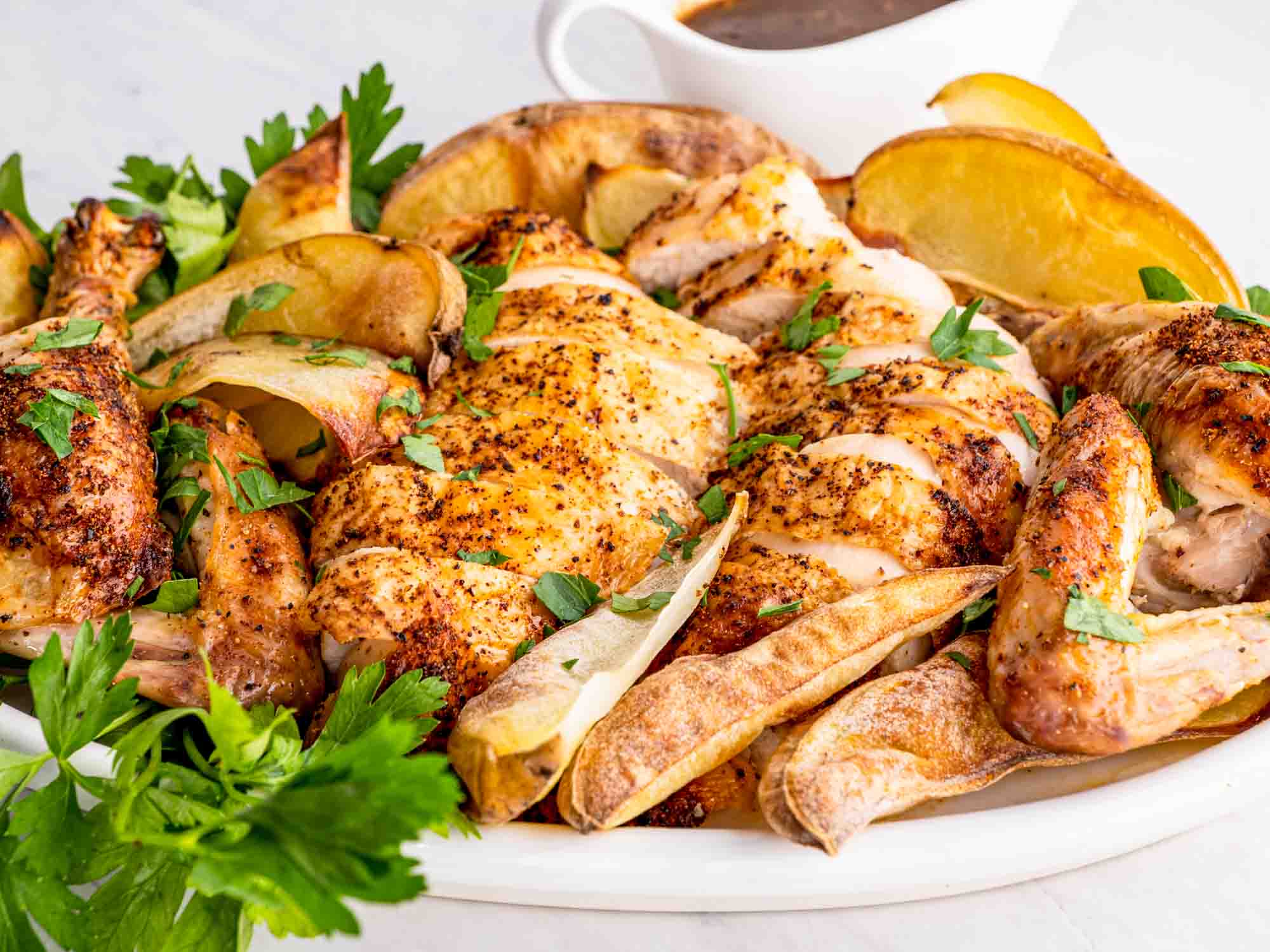 a roast chicken carved from a dish with some roasted potatoes.