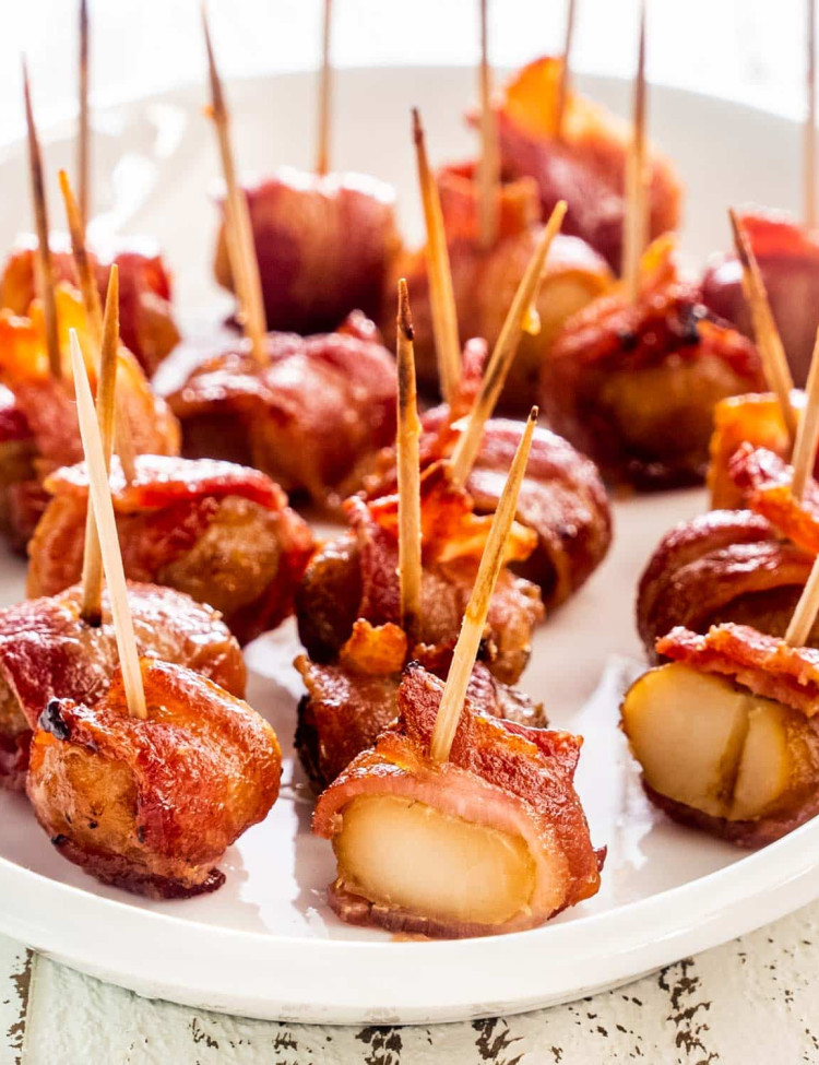 bacon wrapped water chestnuts on a white serving platter.