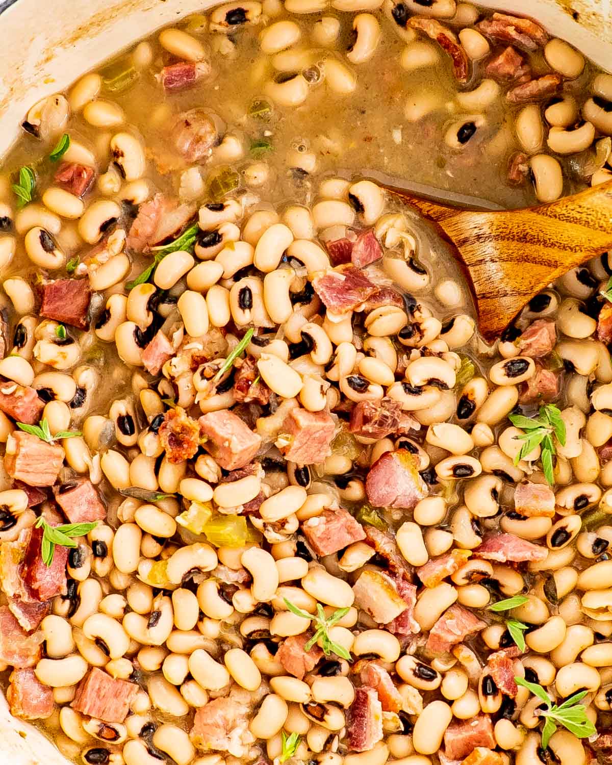black eyed peas in a dutch oven with a ladle inside.