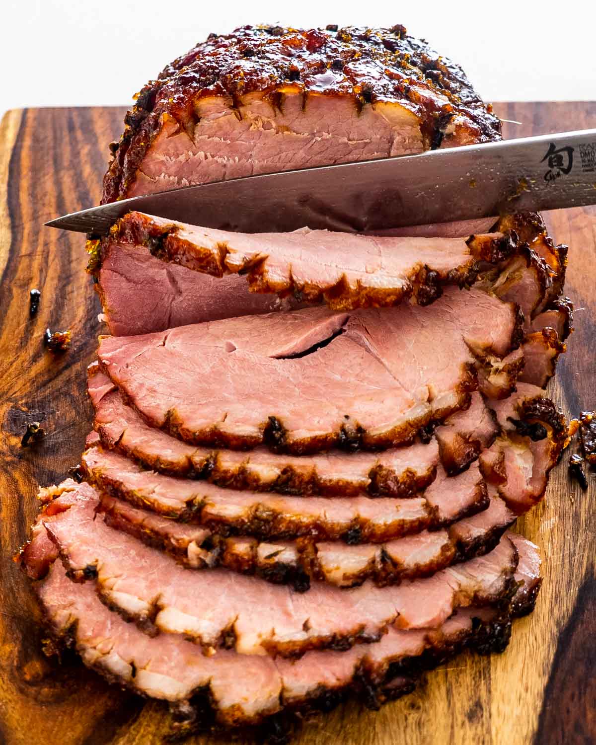 sliced up bourbon glazed baked ham on a cutting board.