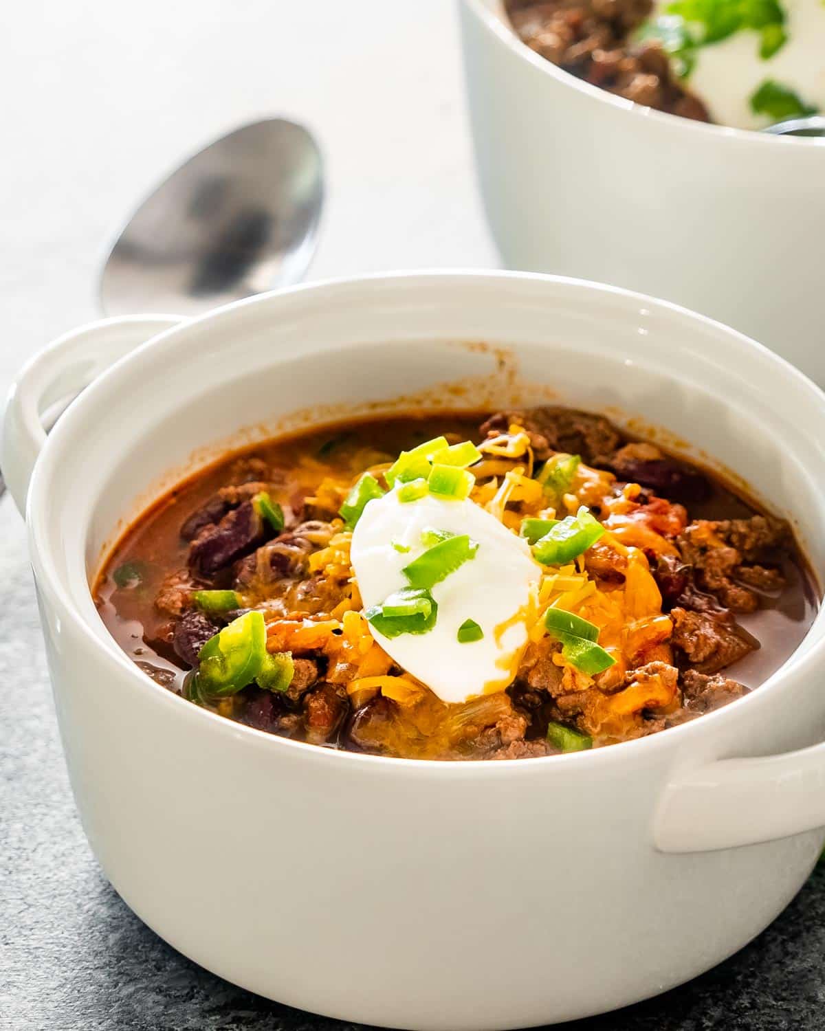 chili in a bowl topped with cheddar cheese and sour cream.