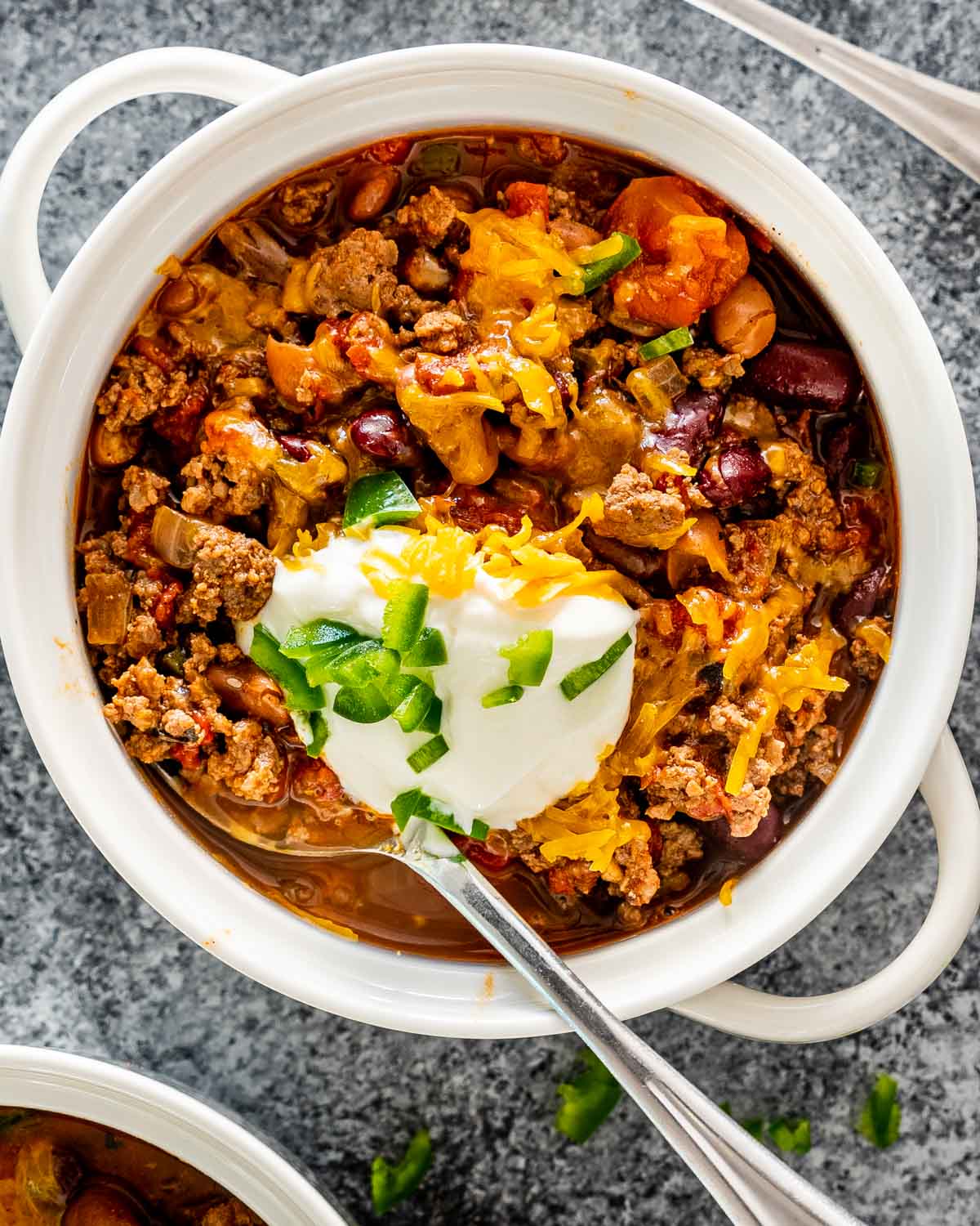 chili in a bowl topped with cheddar cheese and sour cream.