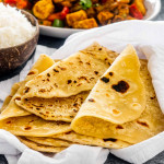 a stack of roti wrapped in a clean kitchen towel.