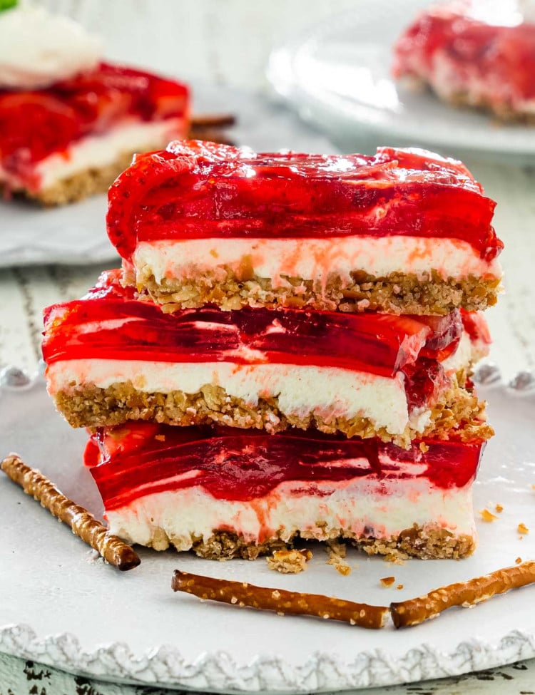 3 slices of strawberry pretzel salad stacked on top of each other on a white dessert plate.