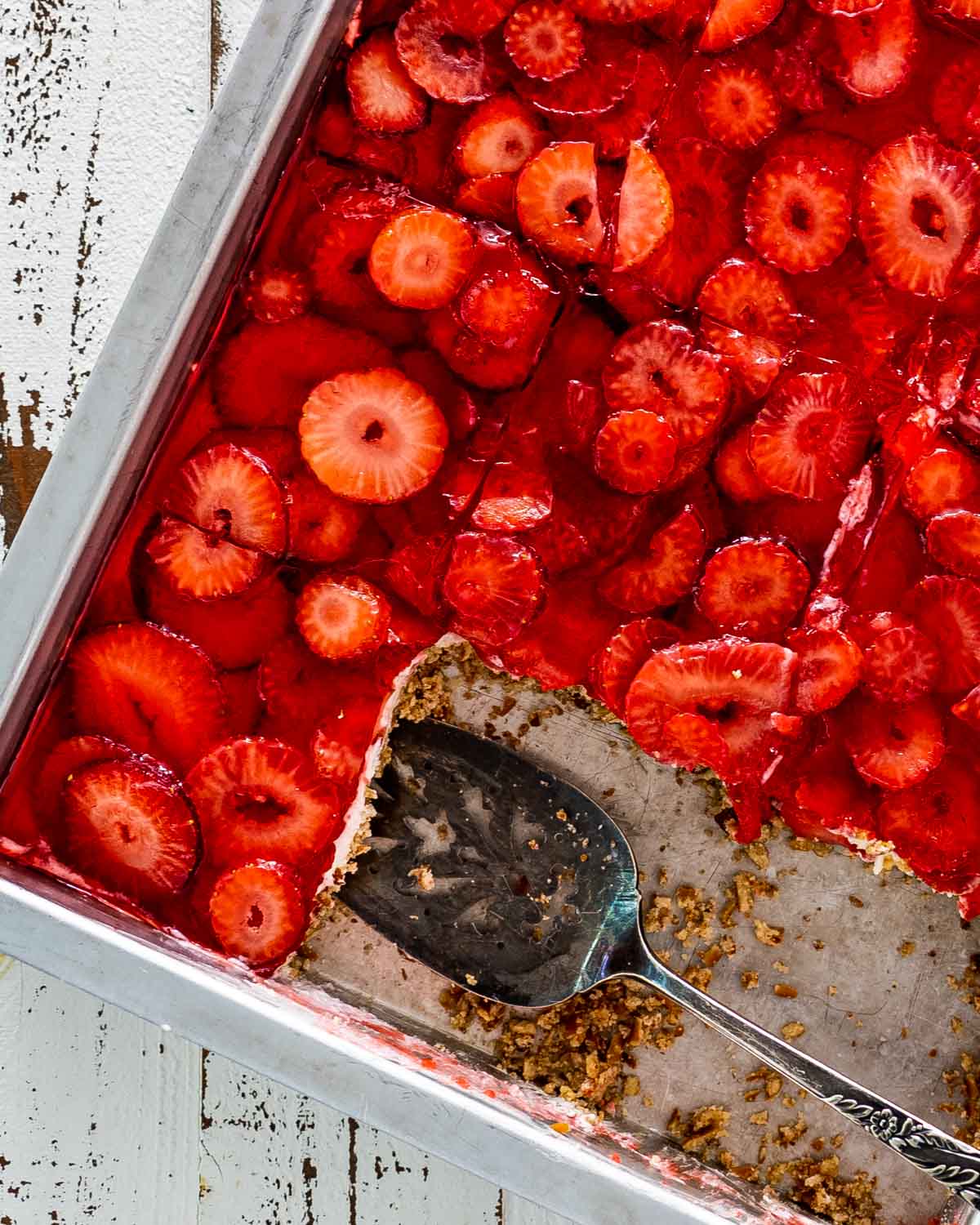 strawberry pretzel salad in a baking dish with a spatula inside.