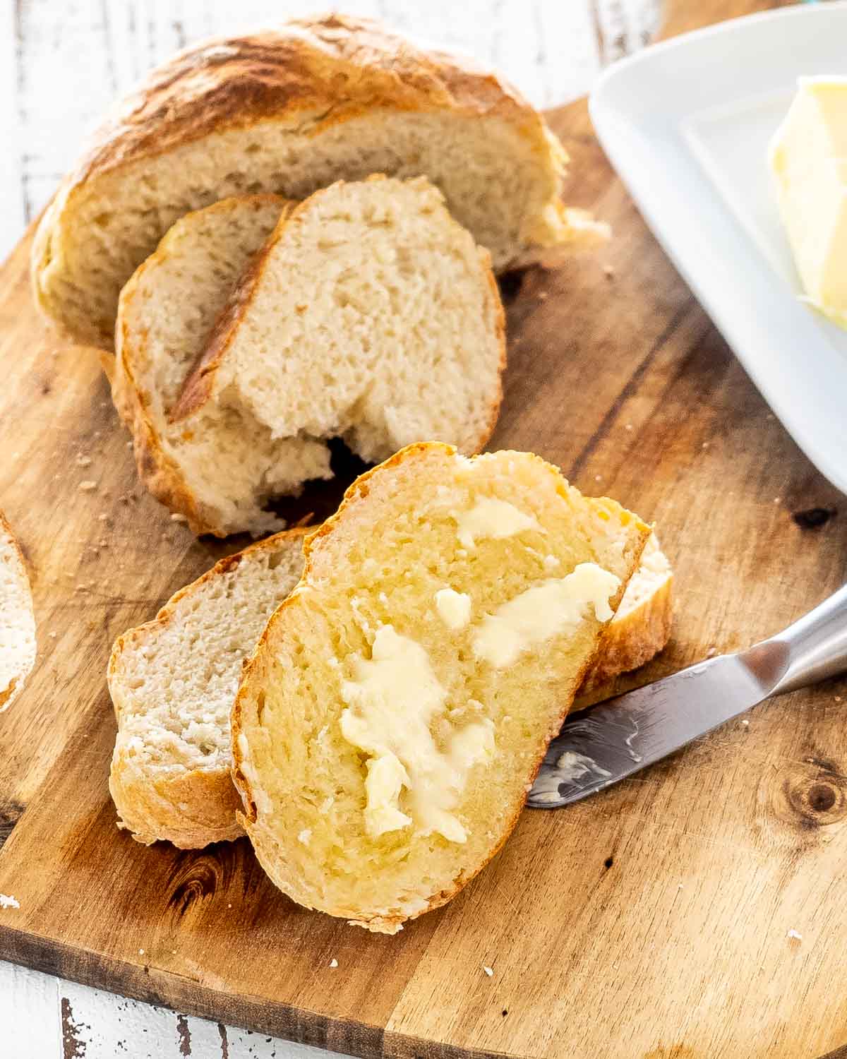 freshly made bread in air fryer on a cutting board cut into slice with butter.
