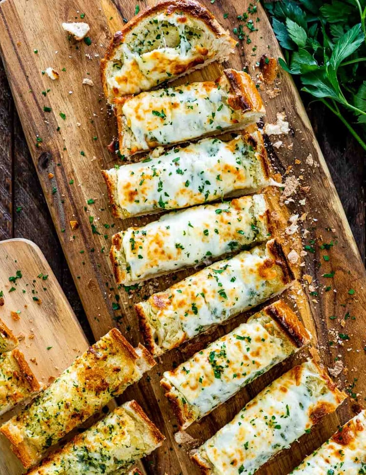 cheesy garlic bread fresh out of the oven sliced on a cutting board.