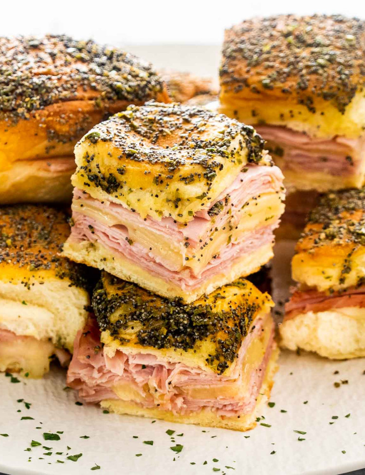 a few stacked ham and cheese sliders on a plate.