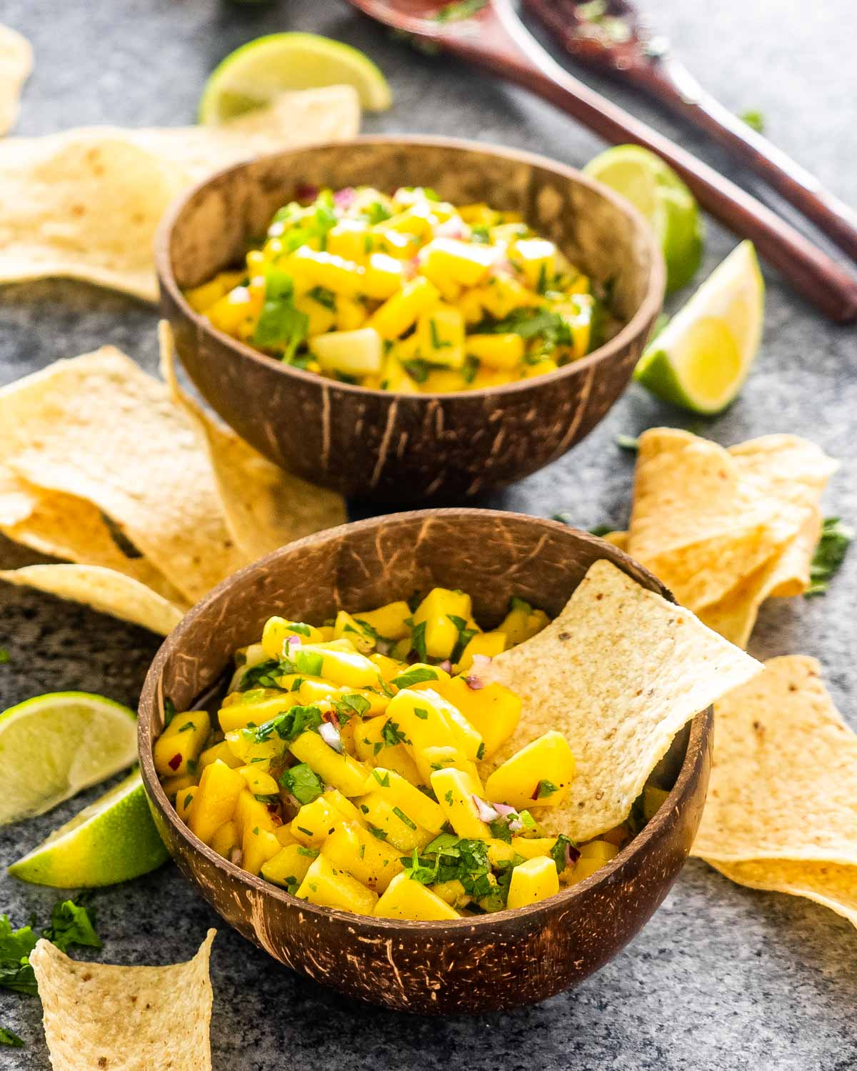 mango salsa in a bowl with a nacho chip in it.