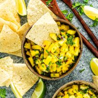 mango salsa in a bowl with a nacho chip in it.