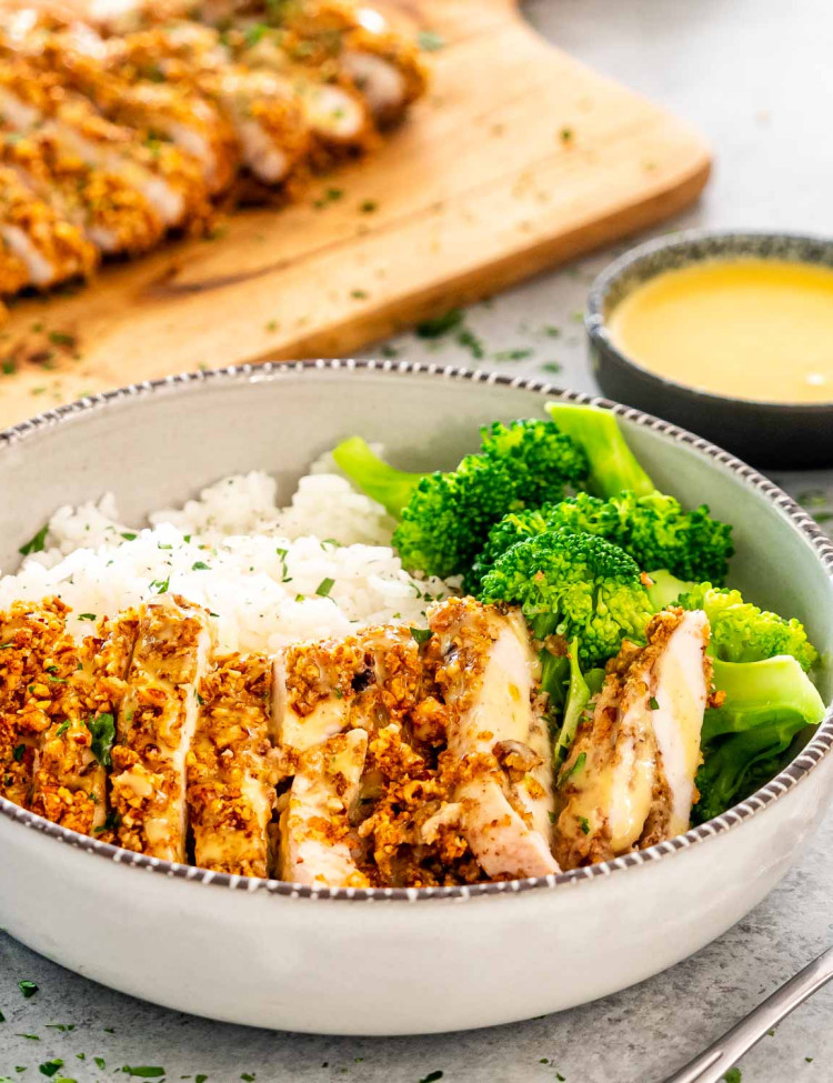 sliced pecan crusted chicken with rice and broccoli.