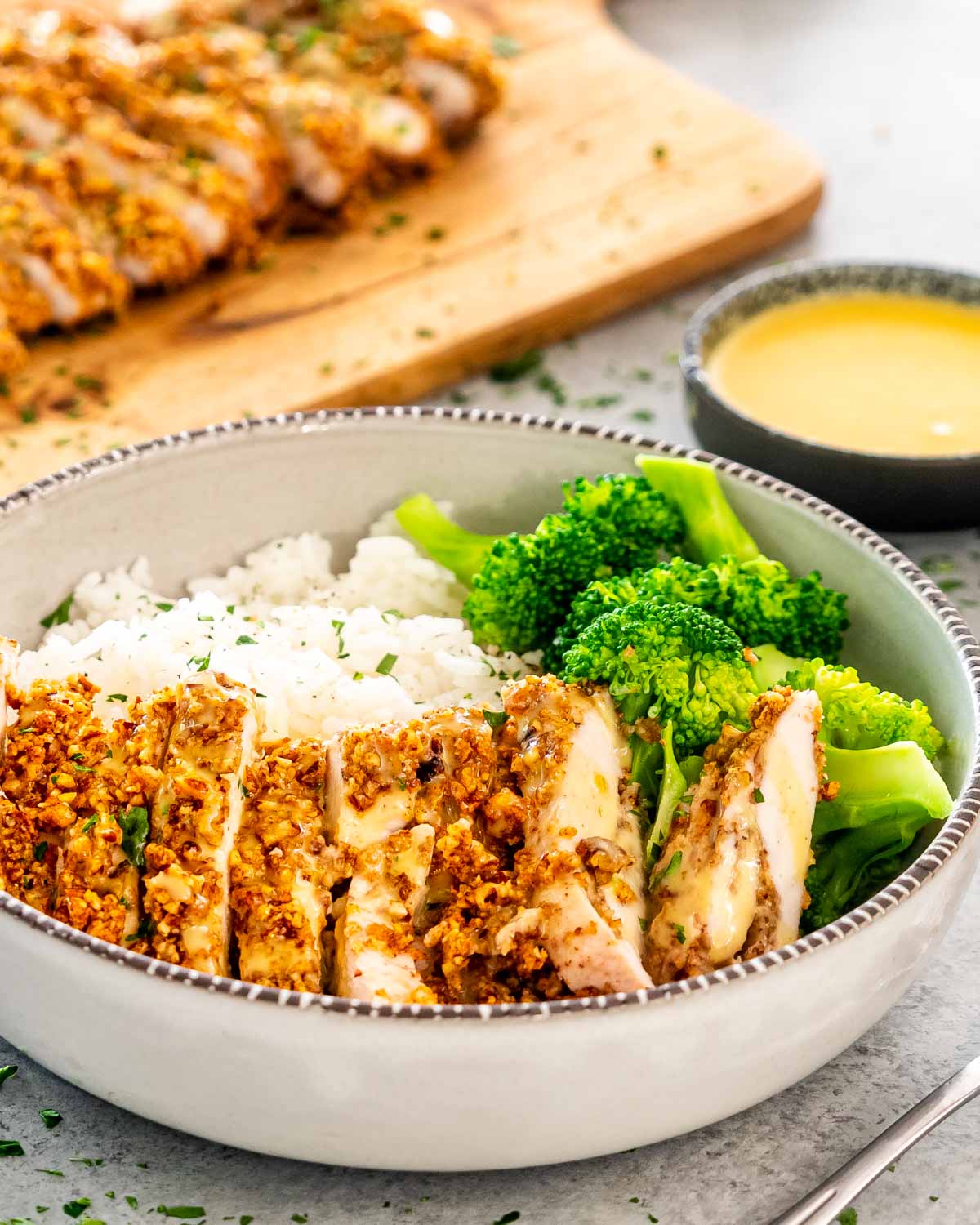 sliced pecan crusted chicken with rice and broccoli.