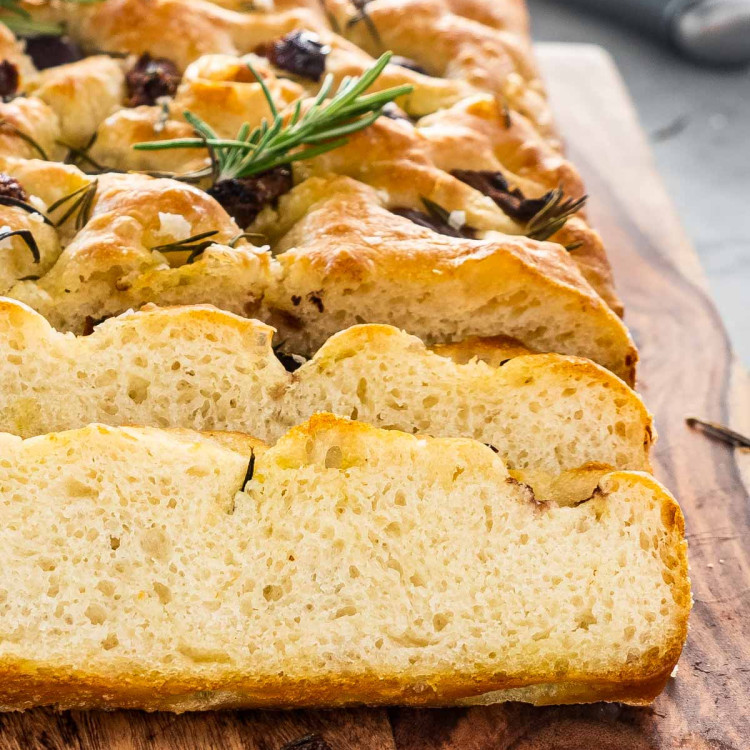 freshly baked focaccia sliced up on a cutting board.