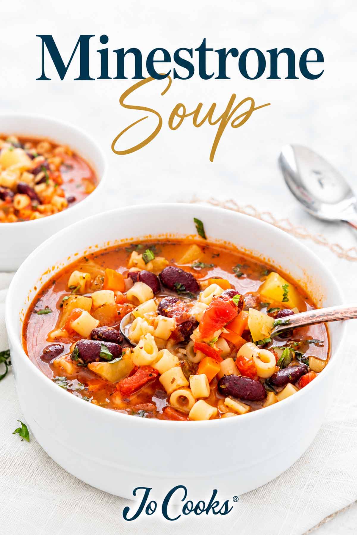 Bowl of minestrone soup with pasta, beans and vegetables beneath a teal and gold title, with Jo Cooks logo.